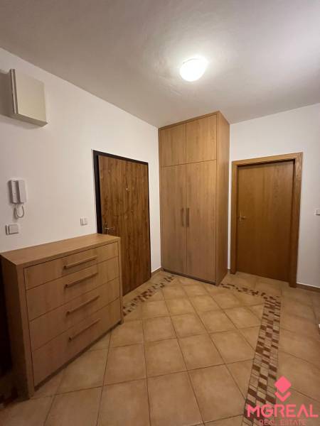 Entrance hall in a 3-room apartment with tiles and cabinets with a wood decor.