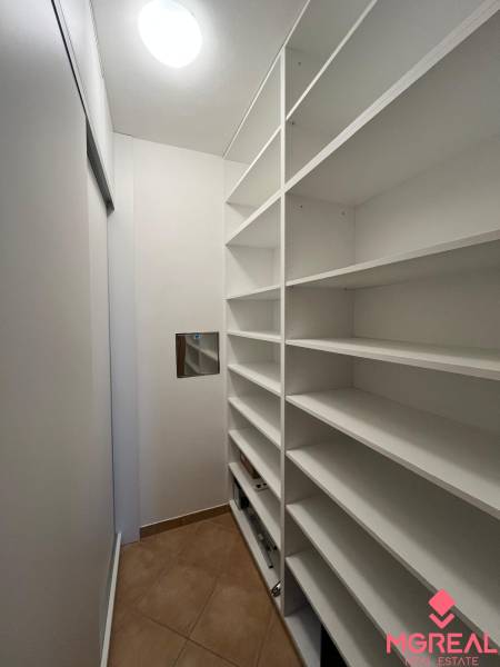 A narrow wardrobe with shelves in a three-room apartment with tiles.
