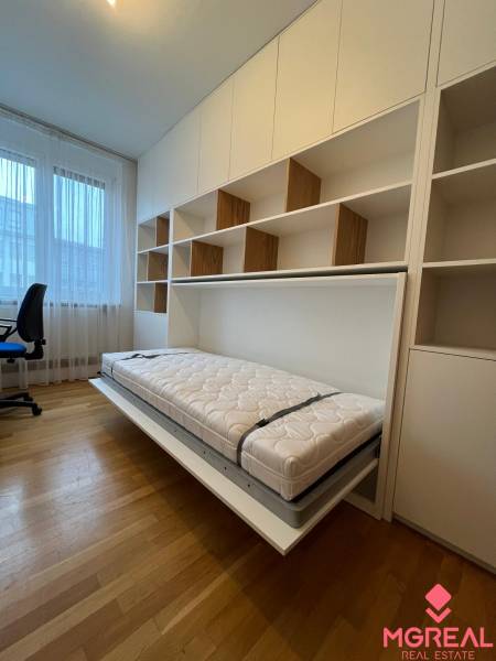 A room in a 3-room apartment with a fold-out bed and a floor with a wood decor.