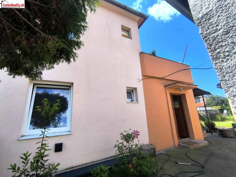 The family house in Partizánske has a pink facade, small windows, and an entrance door.