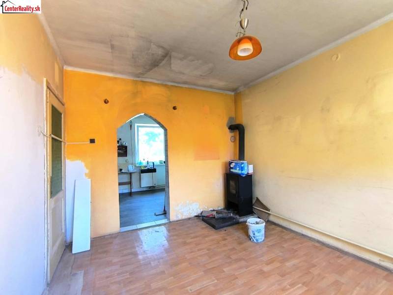 A room in a family house with a stove and a door to the kitchen.