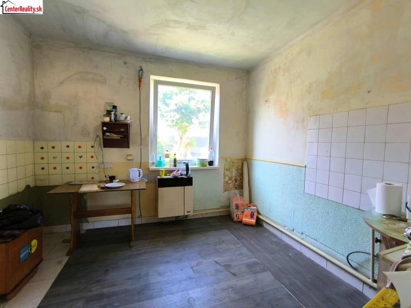 A kitchen in a family house with old furniture, scattered kitchen utensils, a window with a view.