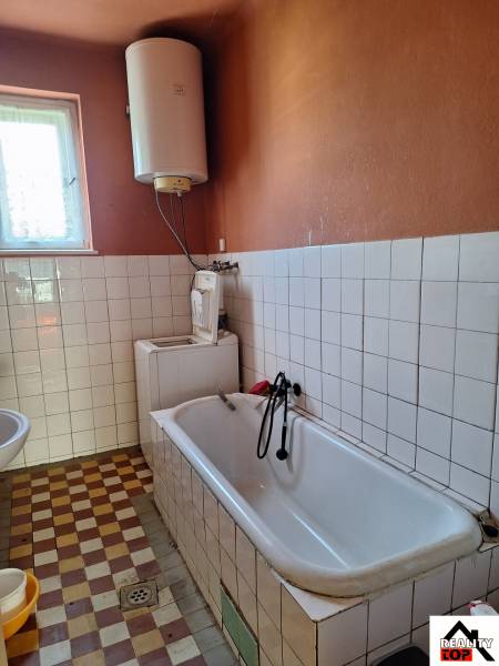 Bathroom in a family house with a bathtub and a water heating boiler.
