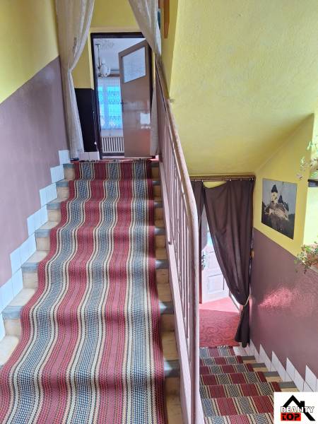 In the interior of the family house, there are stairs with a colorful carpet and curtains.
