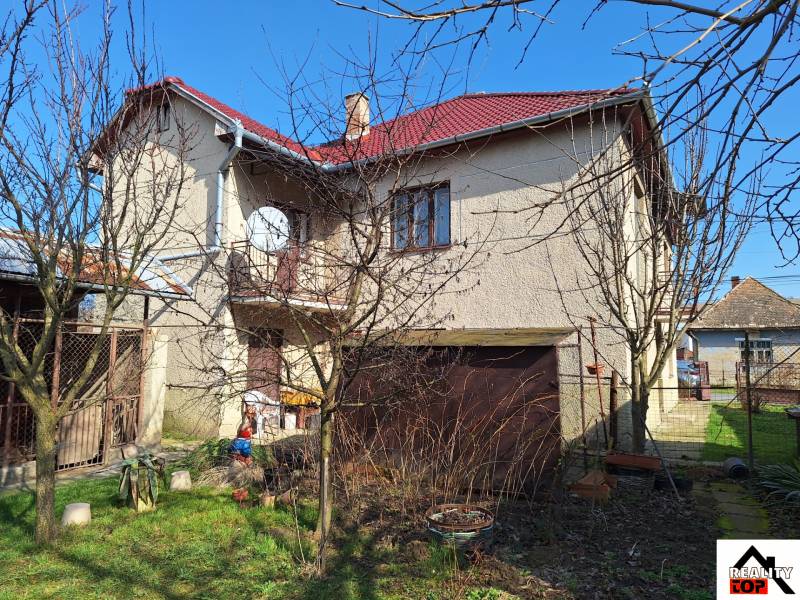 A family house in Tachtoch with a red roof, a garden, and a satellite dish.