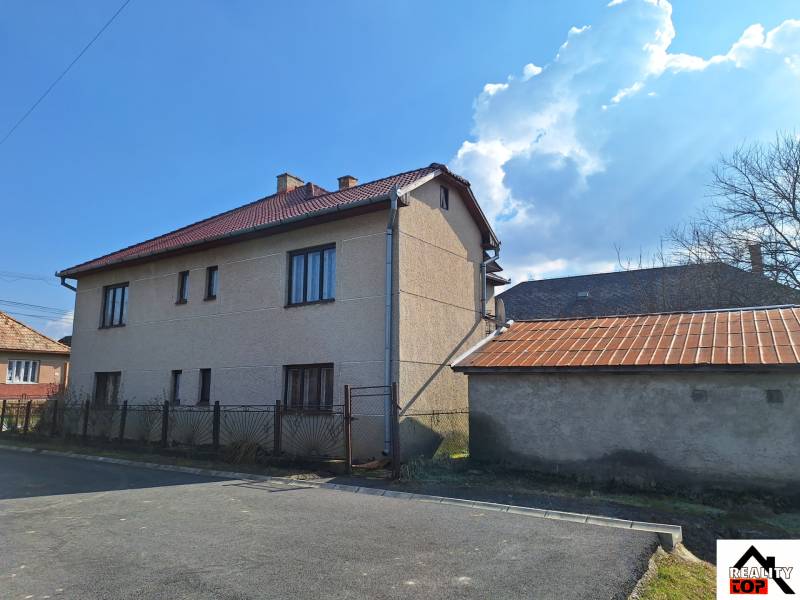 A family house in Tachtá with a red roof and a metal fence on the corner of the street.