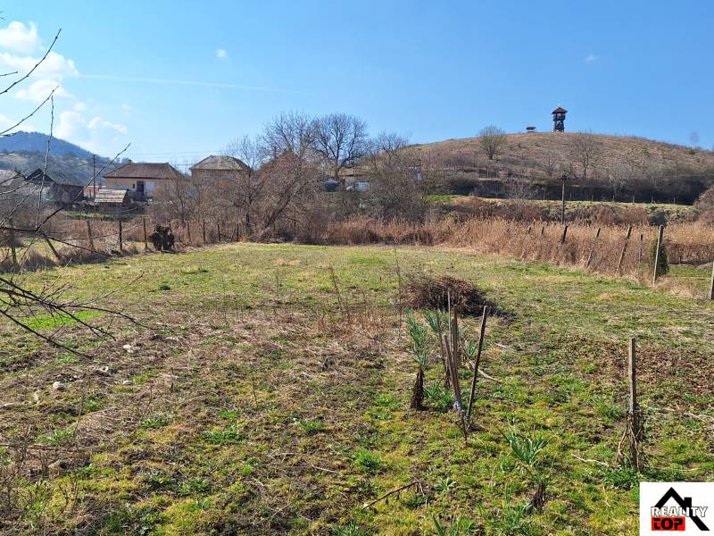 A plot of land near a family house in Tachtá with a rural landscape and a lookout tower on the hill.