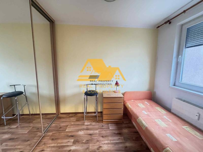 A room with a bed, a cabinet, and a floor with a wooden decor in a 3-room apartment.