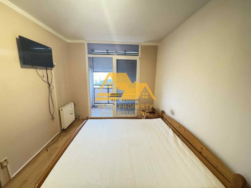 Bedroom in a 3-room apartment with a bed, a TV on the wall, and access to the balcony.