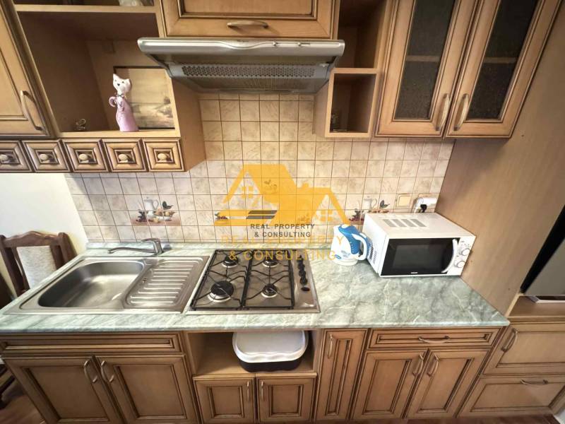A kitchen unit in a 3-room apartment with an extractor hood, microwave, and ceramic tiles.