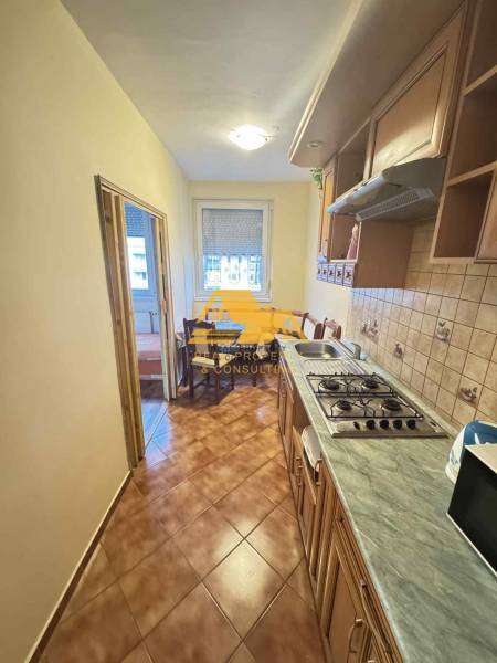 A kitchen in a 3-room apartment with upper cabinets, a stove, and a tiled floor.