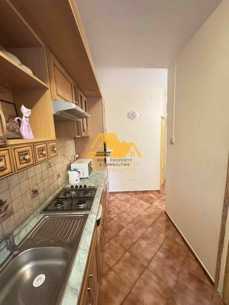 A narrow kitchen in a three-room apartment with a gas stove and ceramic tiles.