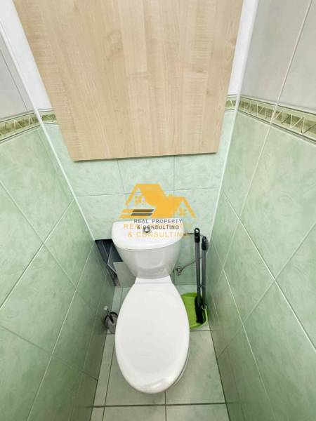 A toilet with green tiles and wooden paneling in a 3-room apartment.