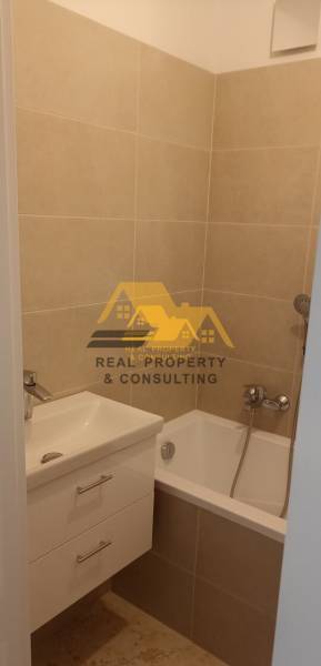 Bathroom with a bathtub and a sink in a 2-room apartment, beige tiles.