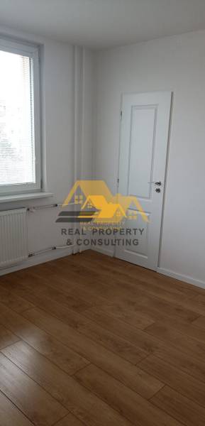 A view of a room with white walls and a floor with a wooden decor in a 2-room apartment.
