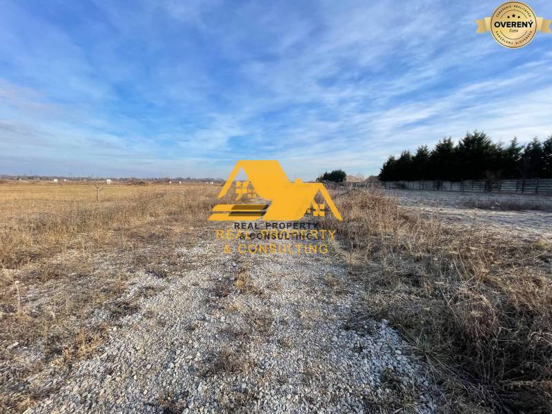 Land for residential use in Nové Zámky on Nové Zámky street, gravel road, open landscape.