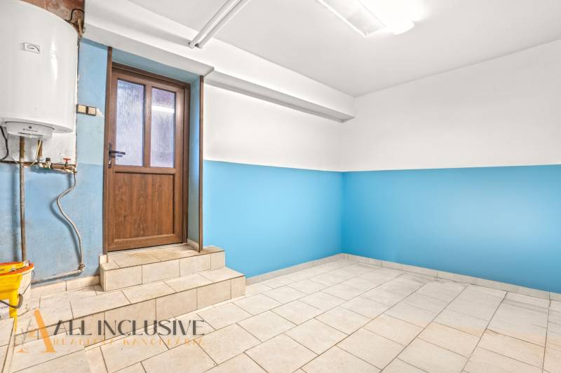 The interior of a family house with blue walls and a light floor next to wooden doors.