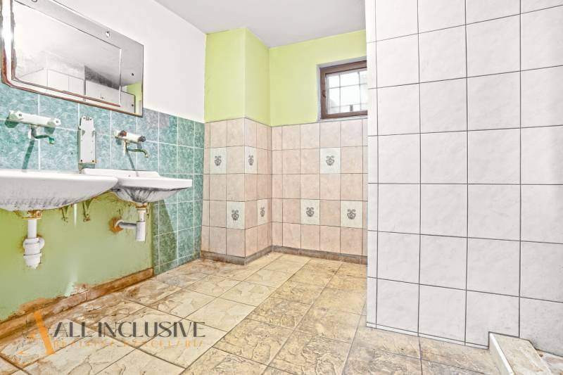 A bathroom in a family house with green tiles and two sinks.