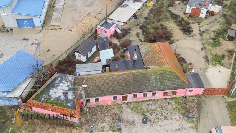 A family house in Šintava with an older pink facade, a concrete yard, and extensions.