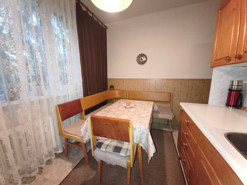 Dining area with a table and chairs in a 3-room apartment with a wooden decor floor.