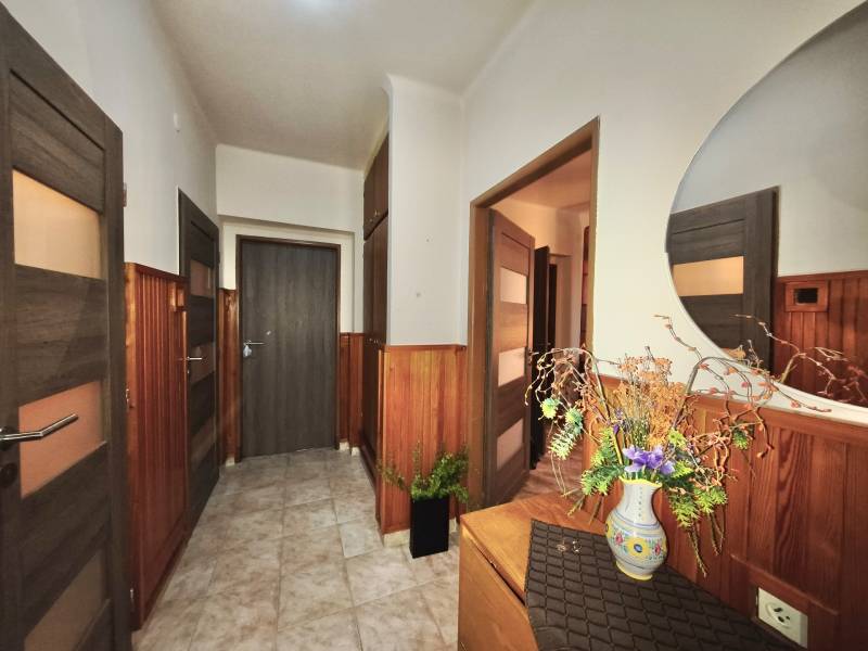 Flower decoration in the hallway of a 3-room apartment with wooden paneling and a mirror.