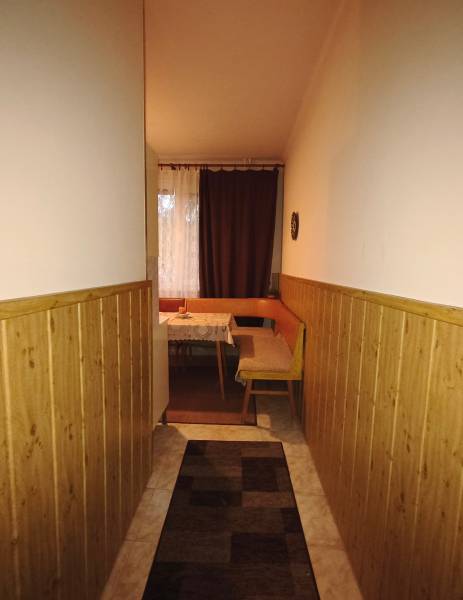 A narrow hallway leading to the dining room with a bench in a 3-room apartment.