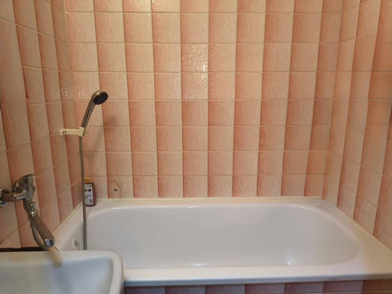 A bathroom in a 3-room apartment with pink tiles and a bathtub.