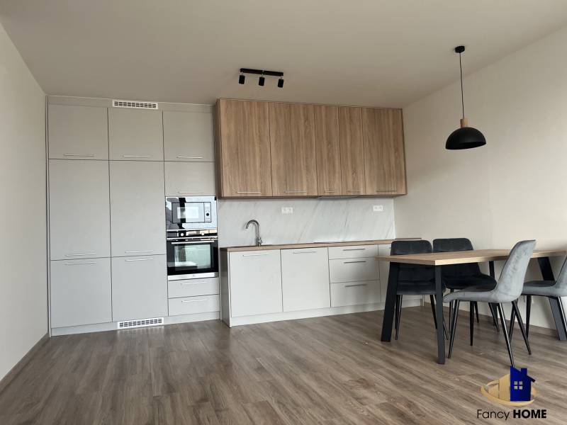 A kitchen in a 2-room apartment with a wooden decor floor and a dining table.
