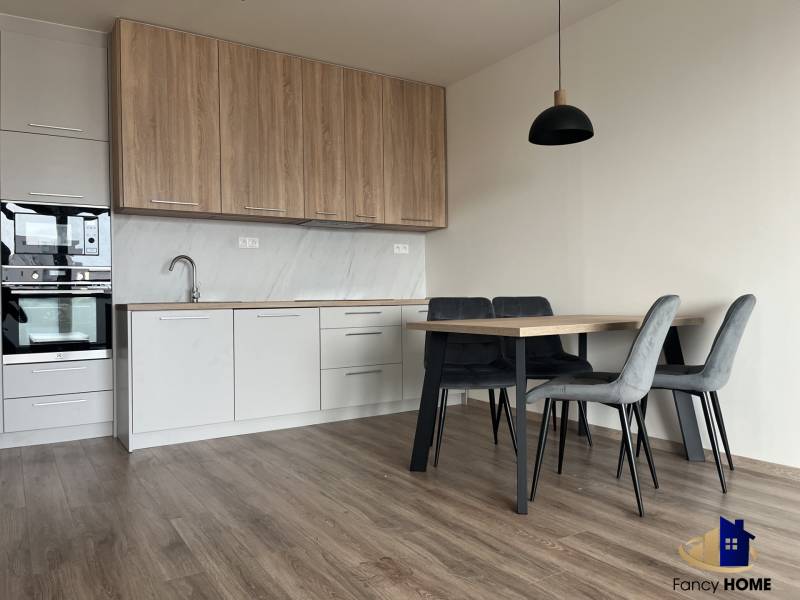 A kitchen in a 2-room apartment with a wooden decor floor and a dining table.