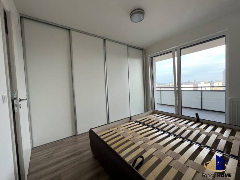 Bedroom in a 2-room apartment with a large built-in wardrobe and a balcony, floor with wood decor.