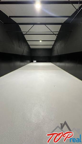 A garage with a white floor and black walls, lighting, empty space.