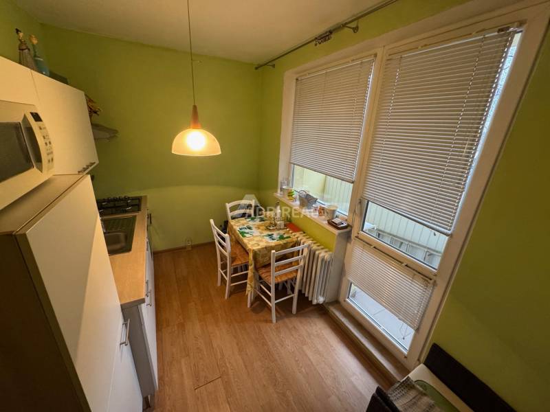 A kitchen in a studio apartment with a table and chairs, wooden decor flooring.