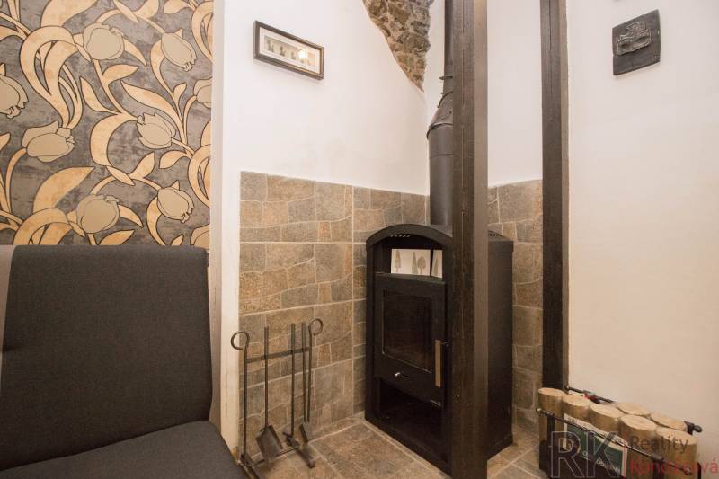 A fireplace with a stone cladding and floral wallpaper in a 2-room apartment.