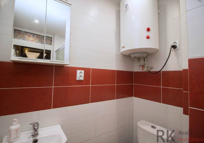 Bathroom with a white boiler, sink, and mirrored cabinet in a 2-room apartment.