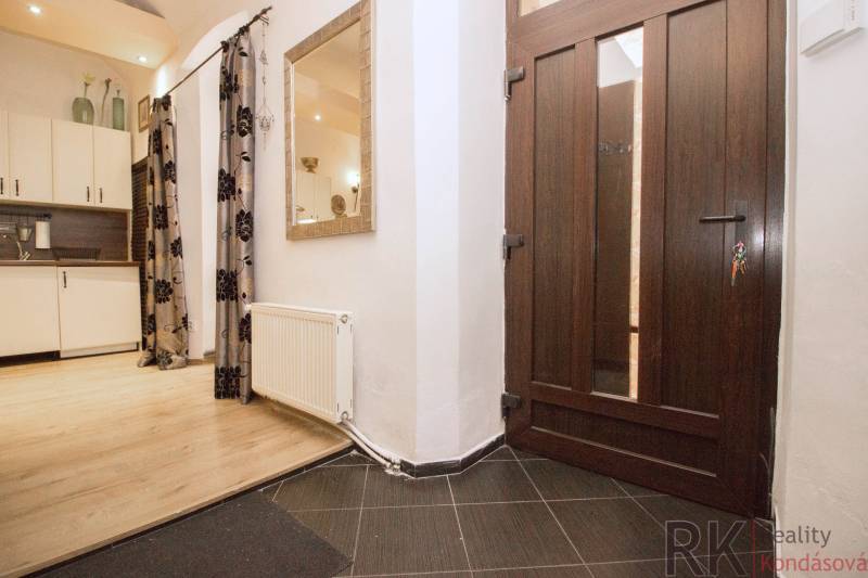 In the 2-room apartment, there is an entrance hallway with a wooden decor floor and an open kitchen.