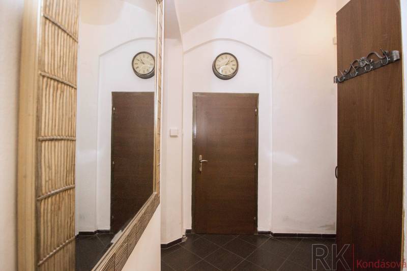 Entrance hallway in a 2-room apartment with dark tiles and a mirror.