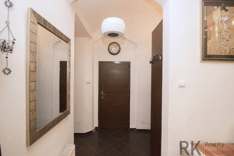 Hallway of a 2-room apartment with a coat rack, mirror, and dark doors, tiled floor.
