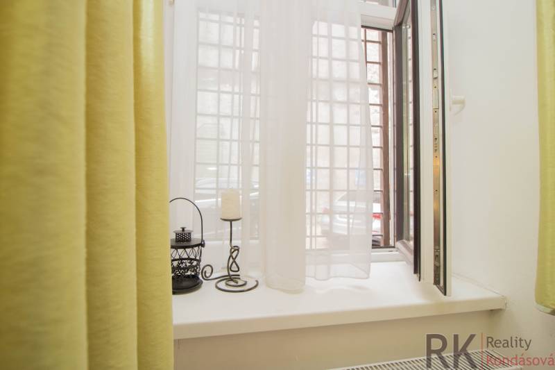 An open window in a two-room apartment with curtains and decorations on the windowsill.
