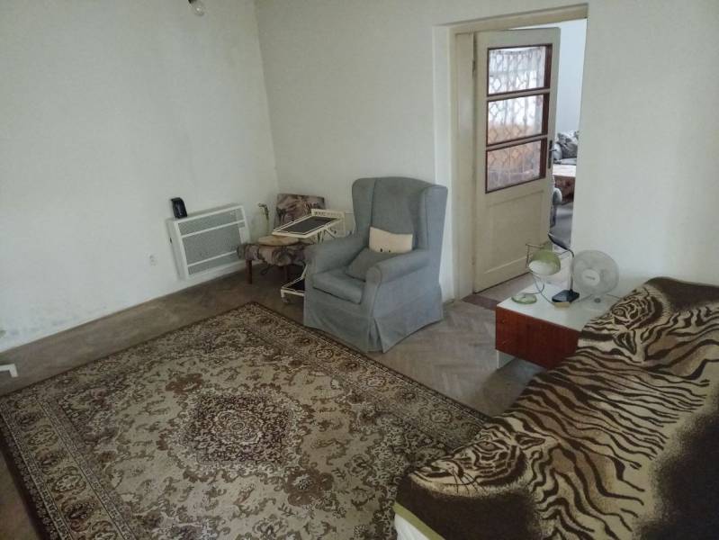 A room in a family house with a carpet, armchairs, and a bed.