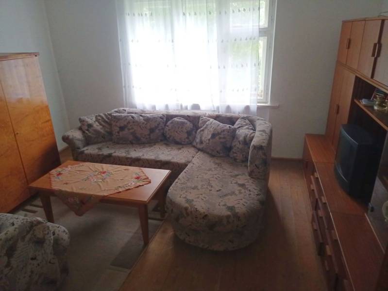 Living room in a family house with a corner sofa and a table on a floor with a wooden decor.
