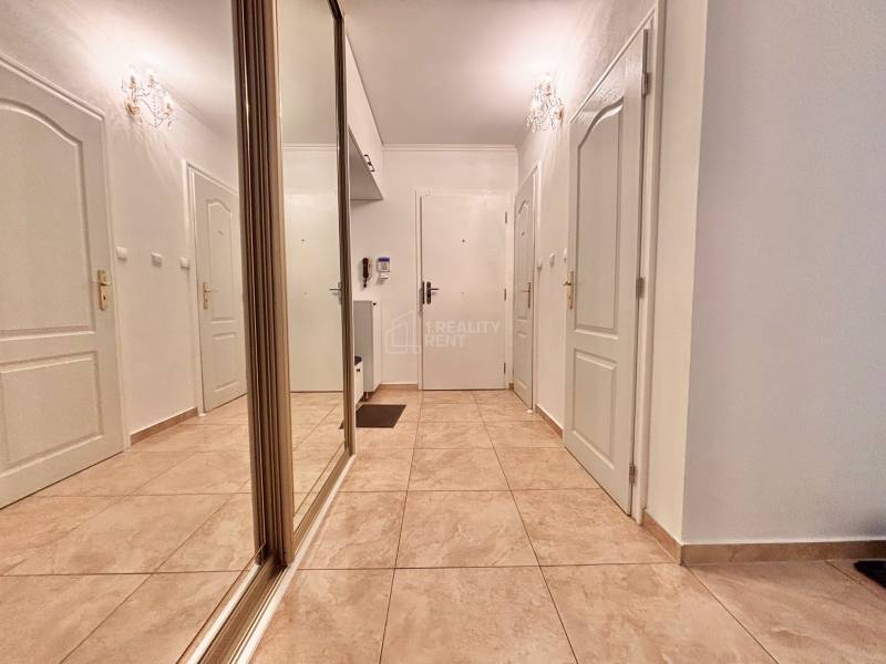 Hallway in a 2-room apartment with tiles, a mirrored wardrobe, and white doors.