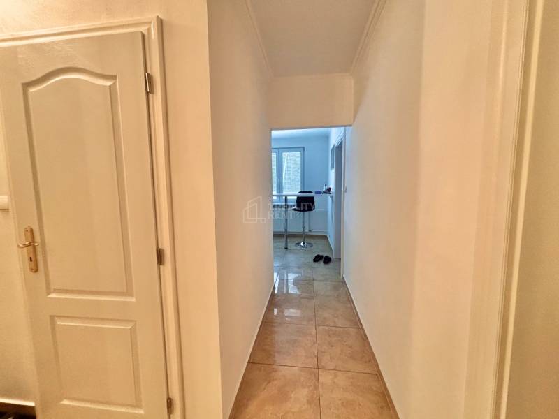 A hallway in a 2-room apartment with tiles and an open view into the kitchen.
