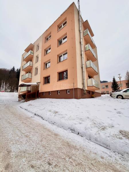 Apartment building in snowy Oščadnica with a 2-room apartment, surrounded by a winter landscape.