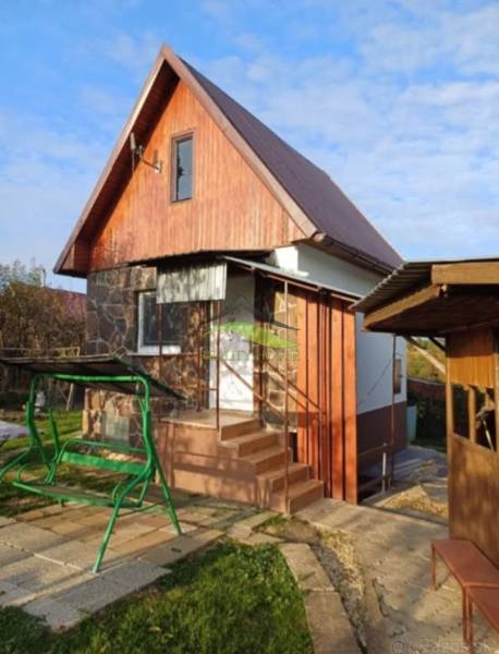 A cottage in Pozdišovce with wooden cladding and a swing in the garden.