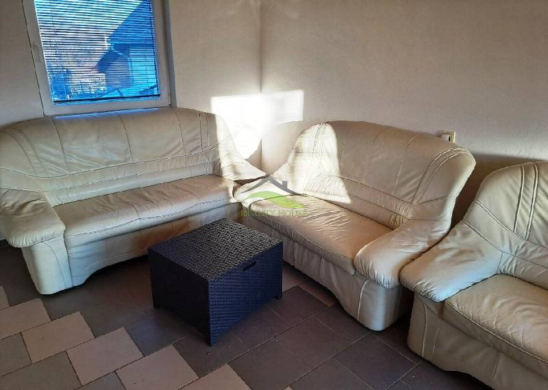 Beige sofa in the cottage with a rattan table, sunlight through the window.