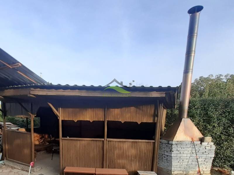 Wooden gazebo and brick chimney by the cottage in Pozdišovce.