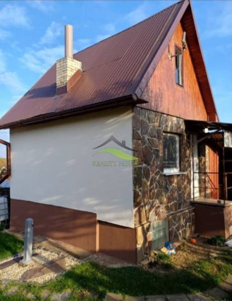 A cottage in Pozdišovce with a stone facade and a brown metal roof.