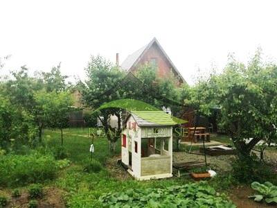 The garden in Pozdišovce with a children's playhouse and fruit trees near the cottage.