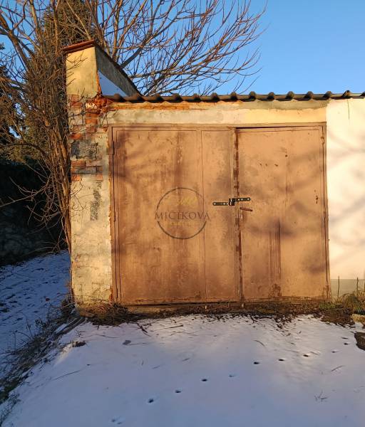 Garages on Fabrická Street in Nitra with simple doors, snowy surroundings.