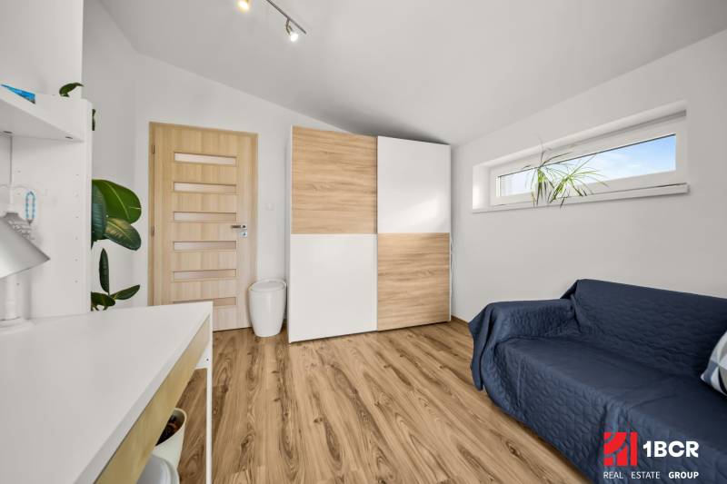 A room in a family house with a wooden decor floor, a wardrobe, and a sofa.